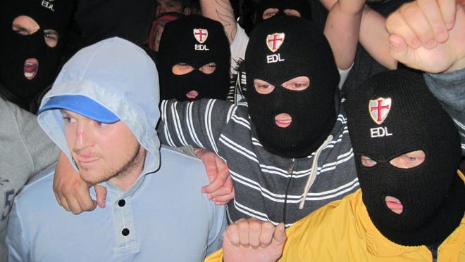 Tommy Robinson, left, the leader of the far-right group, English Defence League leader, with EDL supporters outside The Queens Arms public house in Woolwich, south east London, following the hacking death nearby of a soldier by a man condemning the killing of Muslims by British soldier.