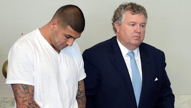 Former New England Patriots tight end Aaron Hernandez, left, stands with his attorney Michael Fee, right, during arraignment in Attleborough District Court Wednesday, June 26, in Attleborough, Mass.