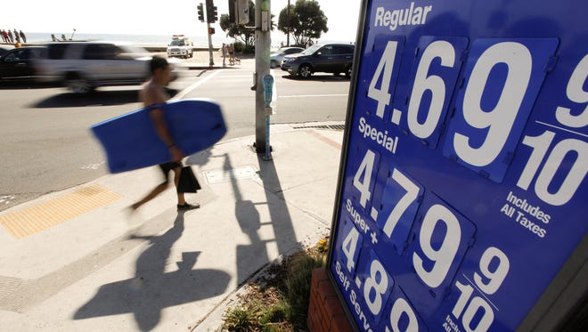 A boogie boarder walks past a sign displaying high gas prices in Laguna Beach, Calif., in 2012.  California's gas taxes are considered high.