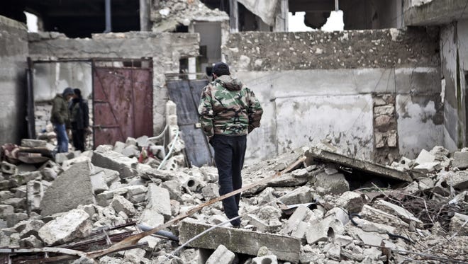A Free Syrian Army fighter walk amid the ruins of a village on Saturday.