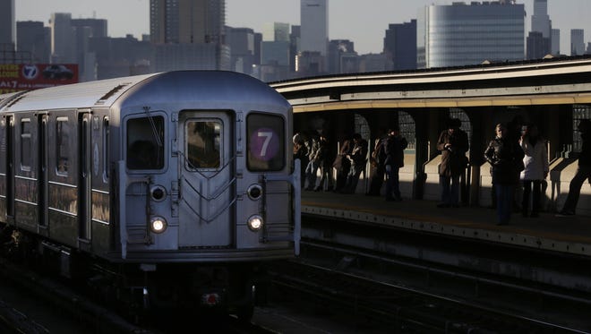 Commuters wait on the platform as a train passes through the 40th St-Lowry St Station, where a man was killed after being pushed onto the subway tracks, in the Queens section of New York, Friday.