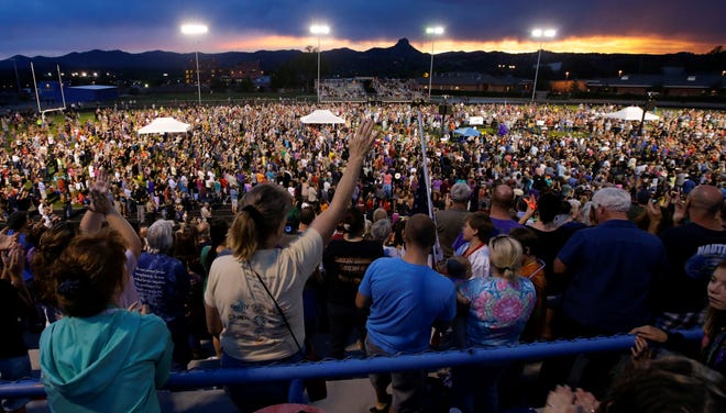 Mourners wave during a community vigil on Tuesday in Prescott, Ariz. for the 19 firefighters from Granite Mountain Interagency Hotshot Crew that were killed battling a wildfire.