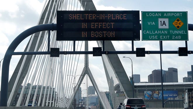 A message calling for citizens of Boston to "Shelter in Place" flashes on a sign on I-93 near the Zakim Bridge in Boston on Friday.