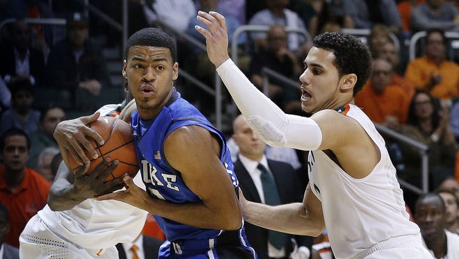 Duke Blue Devils guard Quinn Cook (2) is defended by Miami Hurricanes guard Durand Scott, left, and guard Shane Larkin (0) in the first half of Miami's 90-63 victory.