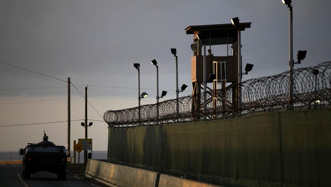 A U.S. trooper stands in the turret of a vehicle with a machine gun, left, as a guard looks out from a tower at the detention facility of Guantanamo Bay U.S. Naval Base in Cuba.
