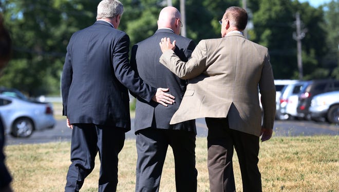 Jeff Leffew, middle, deacon of Colonial Hills Baptist Church is comforted by church members after talking to the media at the church Sunday July 28, 2013, about the bus crash that killed three members.