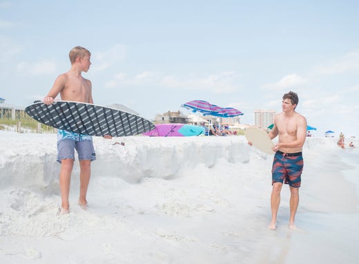 Wyatt West, 14, of New Braunfels, Texas, left, gives Pensacola News Journal sports reporter Eric Wallace a few pointers as he gives skimboarding a try along Penacola Beach on Friday, July 20, 2018.