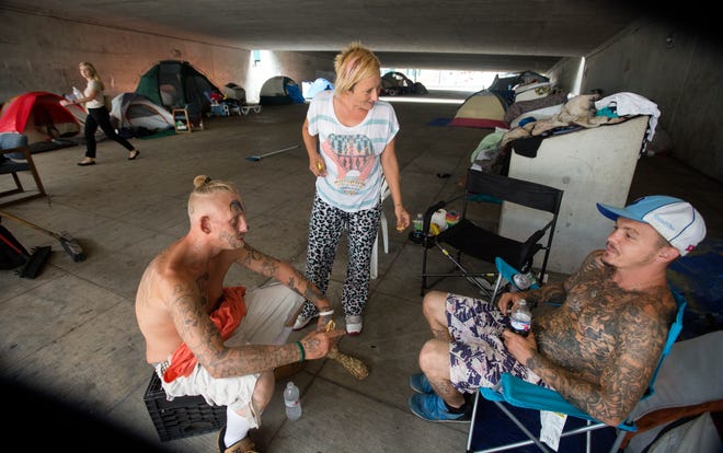 Some of the people living in a homeless camp off third street near the Bengals Stadium will be moved to another temporary location on the east side starting Tuesday. (L-R) Trey, Laura and Bob were unsure where they would be locating next. For the past few months, people who use the breezeway as a cut-through from the parking lot near the Bengals stadium, have complained about the growing homeless encampment. 