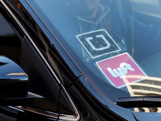 FILE - In this Jan. 12, 2016, file photo, a driver displaying Lyft and Uber stickers on his front windshield drops off a customer in downtown Los Angeles.  (AP Photo/Richard Vogel)
