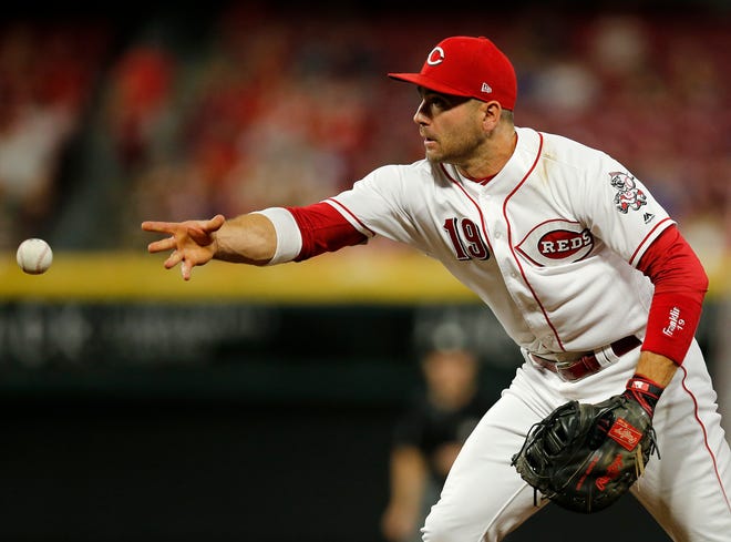 Cincinnati Reds first baseman Joey Votto (19) tosses a ground ball to relief pitcher Jared Hughes (48) for a force out in the eighth inning of the MLB National League game between the Cincinnati Reds and the Philadelphia Phillies at Great American Ball Park in downtown Cincinnati on Friday, July 27, 2018. The Reds won 6-4.