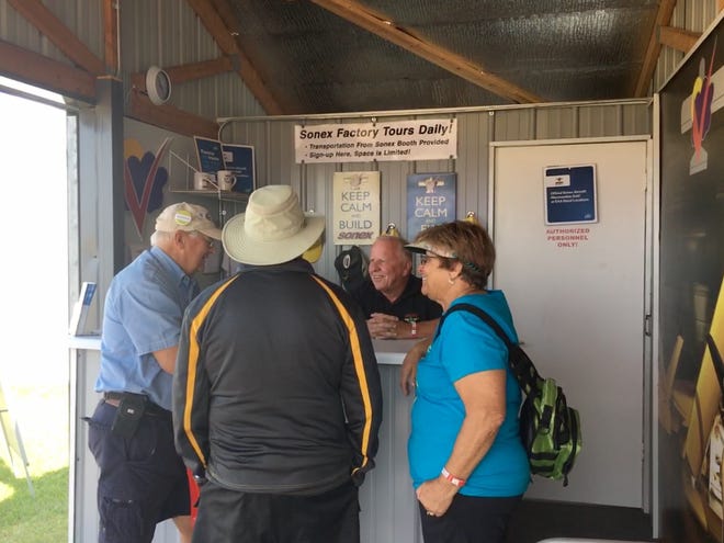 Sonex Aircraft founder John Monnett, with fingers crossed, talks with friends at the Sonex display on Saturday at AirVenture.