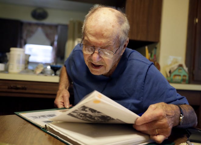 Marvin Staszak, a resident of Krakow, looks through a scrapbook of historic pictures of the community while sitting in his kitchen.