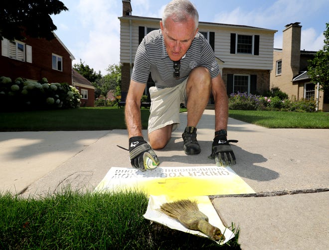 Shorewood Historical Society President Bob Dean sprays non-permanent yellow and white chalk through a stencil on Ridgefield Circle on Aug. 3 to promote purchase of home birthday markers.
