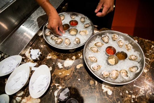 Ruben Ramos places a piece of paper that designates the oyster varieties for dinner guests at Sea Salt in downtown Naples on Thursday, August 2, 2018. 
