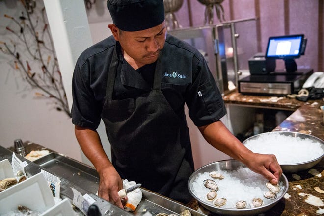 Ruben Ramos plates a freshly shucked oyster while preparing an order at Sea Salt in downtown Naples on Thursday, August 2, 2018.