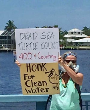A protestor on the Matlacha Bridge on Sunday raises signage highlighting issues with water in the Caloosahatchee River and off the coast of Lee County.