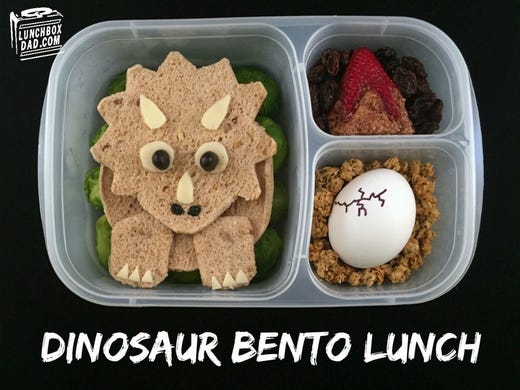 Dinosaur lunch includes whole wheat bread or sandwich thins, white cheesesandwich filling, vegetable background,  granola, hard boiled egg, raisins, cream cheese, strawberry, graham crackers or cereal crumbs and black food coloring.