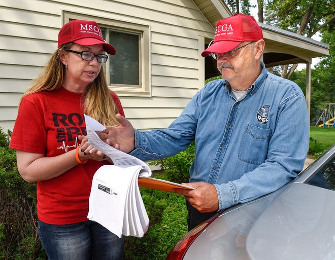 Liz Baklaich and John Palmer of the citizen group Concerned Community Citizens look at the signatures volunteers collected Friday, Aug. 3, to try to add a refugee resettlement resolution to the Nov. 6 ballot.