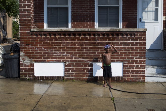 Mikal Harris holds a water hose as he plays with his friends on Lamotte Street during a heatwave in July in Wilmington.