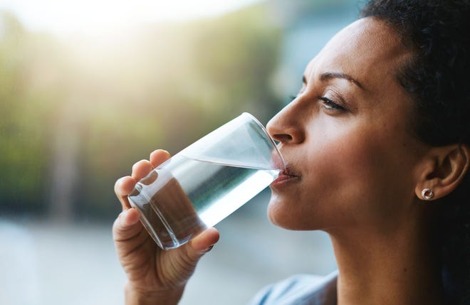 Shot of a woman drinking a glass of water at home