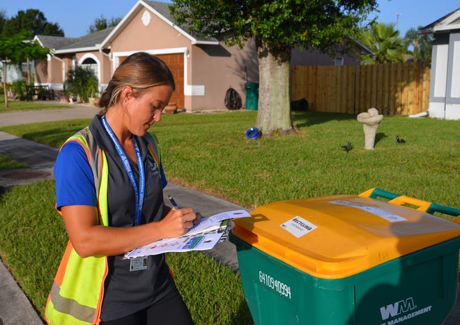 Michelle Smith, Melbourne environmental programs coordinator, checks a recycling cart Wednesday morning in the Feather Lakes neighborhood.