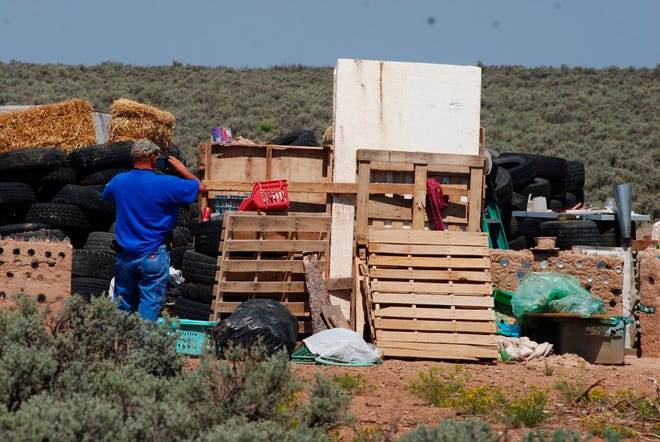 Taos County Solid Waste Department Director Edward Martinez surveys property conditions at a disheveled living compound at Amalia, N.M., Tuesday, Aug. 7, 2018. The investigation into a group of starving children found in the desert compound in New Mexico took another dark turn Tuesday, when authorities said they found the remains of a young boy at the squalid property.