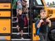 Students race off the bus at the new McCutchanville Elementary school for the first day of school Wednesday, August 8, 2018. 