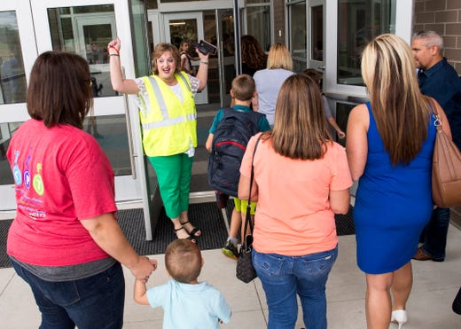 McCutchanville Elementary school principal Lisa Shanks, middle, opens the doors for the first time with a cheer while students arrive for the first day of school Wednesday, August 8, 2018.