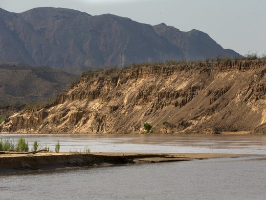 A boat passes silt banks towering more than 50 feet above the banks of the Colorado River near Pearce Ferry on Aug. 1, 2018. The silt in the banks, which make the end of the Grand Canyon in Lake Mead National Recreation Area, came down the Colorado River and could not pass Hoover Dam. The banks were once underwater, but now line the river with the lake at near-record-low levels.