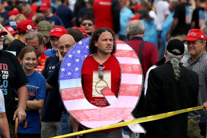 David Reinert holds a large "Q" sign while waiting in line on to see President Donald J. Trump at his rally Aug. 2, 2018 at the Mohegan Sun Arena at Casey Plaza in Wilkes Barre, Pa. "Q" represents QAnon, a conspiracy theory group that has been seen at recent rallies.