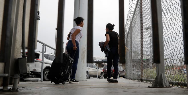In this June 20, 2018, file photo, sisters from Guatemala seeking asylum, cross a bridge to a port of entry in to the United States from Matamoros, Mexico, in Brownsville, Texas.