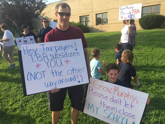 Brian Larkin (left) and his son Kevin hold up their signs at the rally at Teddy Bear Academy in Marlton held a few months ago.