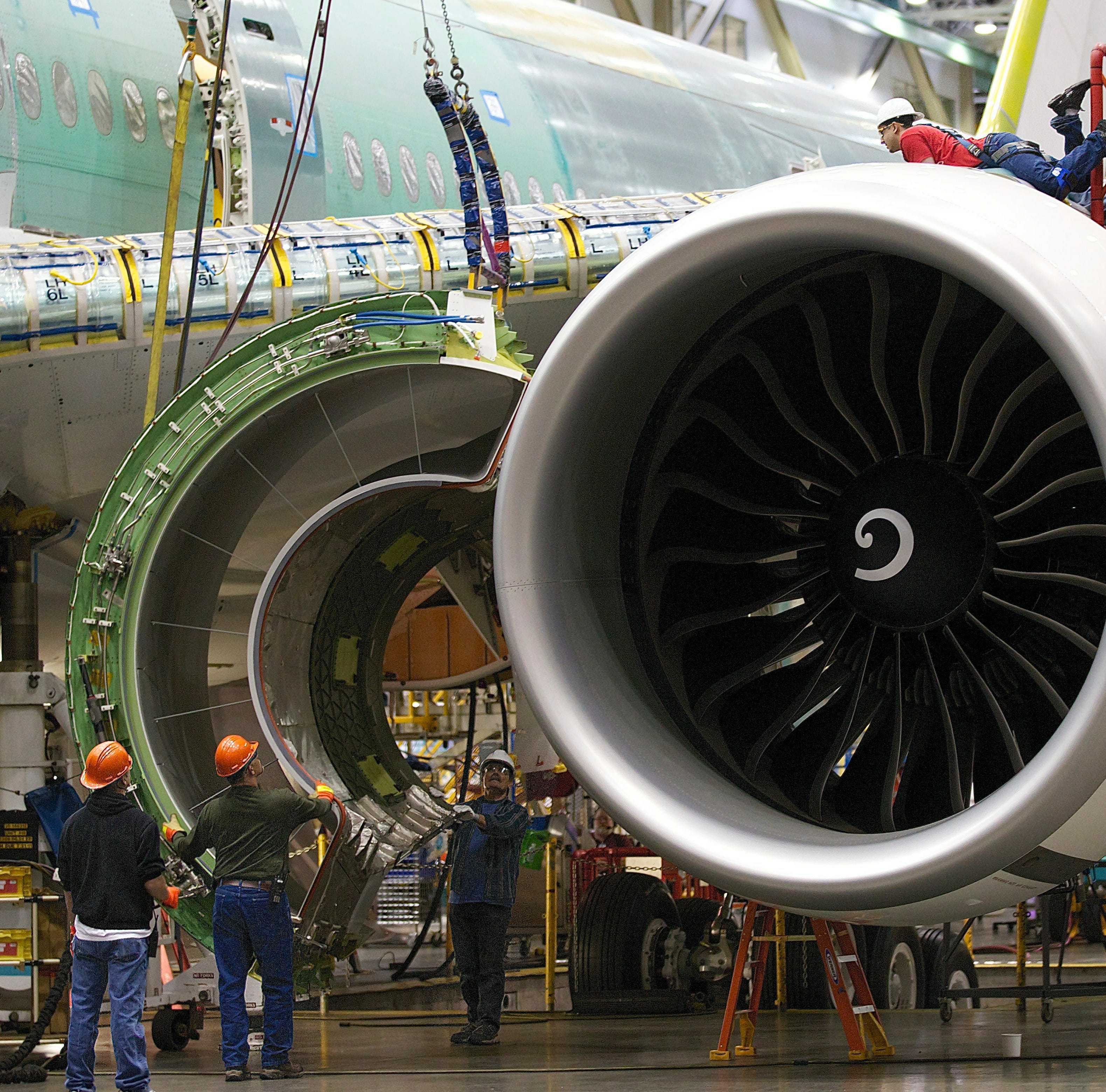 Boeing employees prepare to install an engine cowling on a Boeing 777 passenger plane at the company's factory in Everett, Washington.