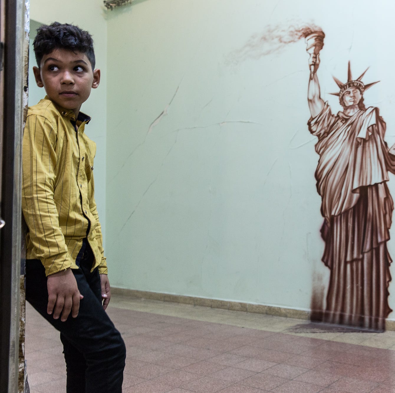 An unidentified child stands near a mural of the Statue of Liberty inside the former U.S. Embassy in Tehran, Iran, on July 11, 2018.