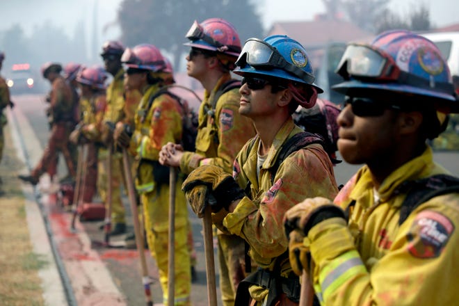 Fire crews line up as they watch a wildfire on a ridge top while protecting a residential area from the Holy Fire on Friday in Lake Elsinore.