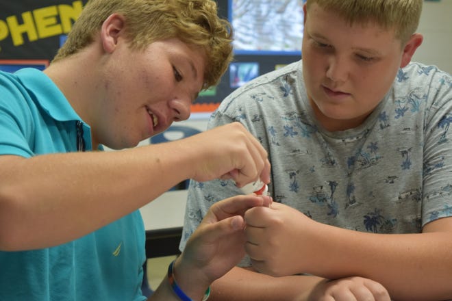 Carter Middle School students Nate Harrell, left, and Braxton Purkey add a chemical solution to the experimental tooth sent to the International Space Station on Sunday, Aug. 12, 2018.
