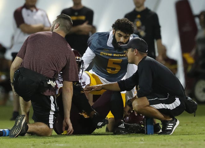 ASU's Manny Wilkins (5) checks on Tyler Whiley (23) after he goes down with an injury during the ASU scrimmage at Kajikawa Practice Fields in Tempe, Ariz. on Aug. 11, 2018.