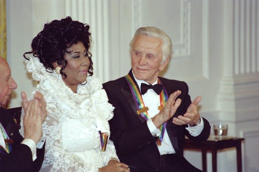 US actor Kirk Douglas (R) applauds singer Aretha Franklin at a reception for the Kennedy Center Honors on December 04, 1994 at the White House in Washington DC. The Kennedy Center Honors recognizes American performance artists who have made lifetime contributions to American culture. Person at left is unidentified. AFP PHOTO JOSHUA ROBERTS (Photo credit should read JOSHUA ROBERTS/AFP/Getty Images)