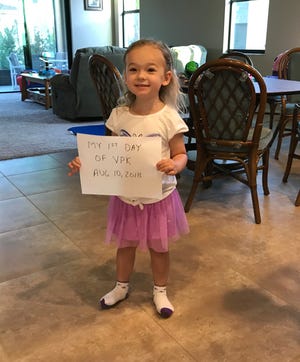 Isabella poses with her father's home made sign prior to her first day of VPK.