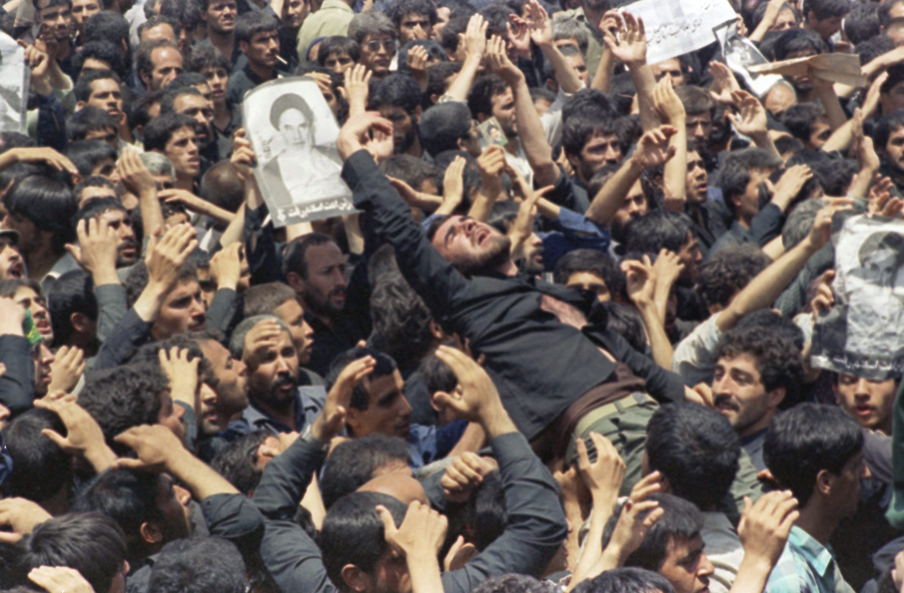 An Iranian mourner goes into a frenzy just after the body of the Ayatollah Khomeini was removed from Beheshte Zahra Cemetery on June 6, 1989, Tehran, Iran. The burial was delayed when thousands of mourners crowded the Imams body in an effort to touch their leader.