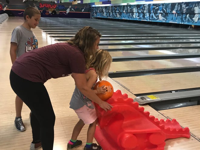 Laurie K. Blandford teaches her 5-year-old niece, Finley, how to bowl while 9-year-old nephew Connor watches.