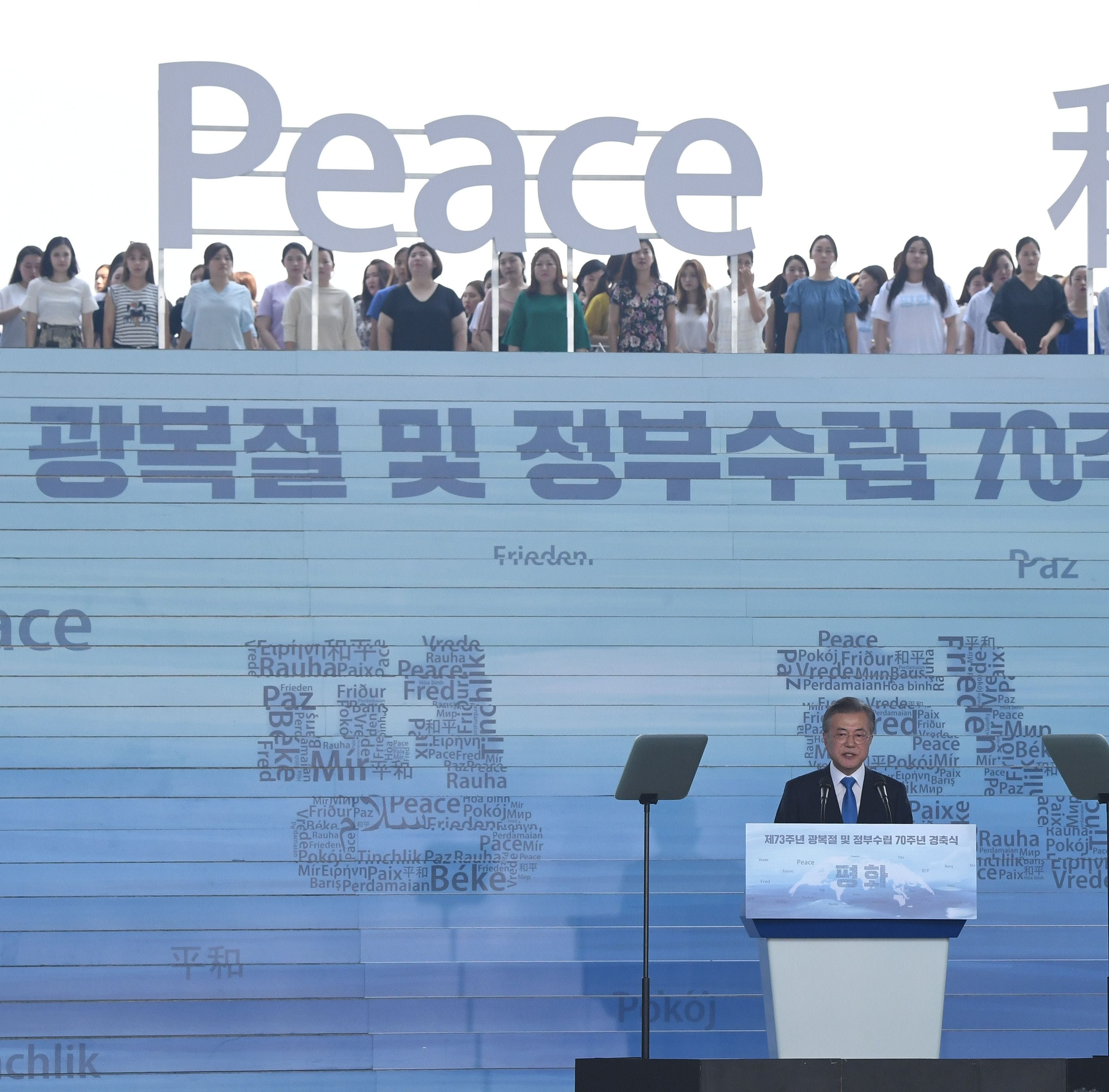 South Korean President Moon Jae-in delivers a speech as characters and letters reading 