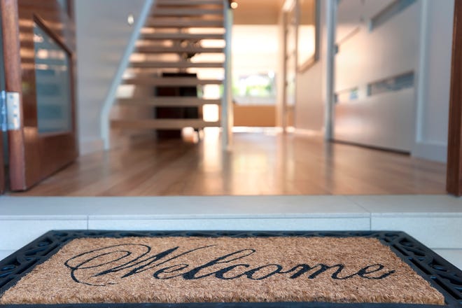 Close up of a welcome mat in front of an inviting house.