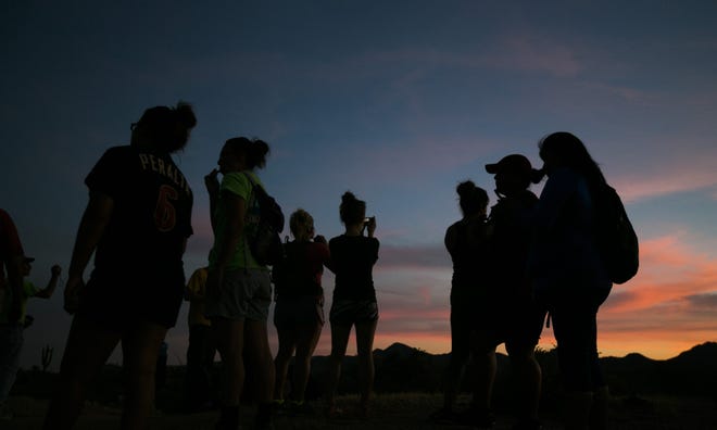 People take a quick stop to take photos of the cactus and sunset at McDowell Mountain Regional Park in Fountain Hills, AZ