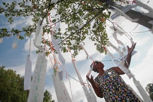 Beverly A. Stanton, a former Roman Catholic nun, looks through a tree with hanging prayer flags that were hung by community members in a demonstration against the principles of the Ku Klux Klan group that appeared in Gettysburg in 2013. People of all faiths and nationalities gathered at the Lutheran Seminary to show a sign of unity against the white separatist and anti-Obama messages of the KKK.