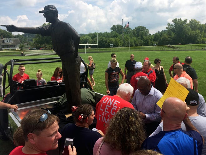 Fans surround two-time Heisman Trophy winner Archie Griffin, who signs autographs next to a statue of former Ohio State coach Woody Hayes at Lee Stadium in Newcomerstown. The statue, erected by Zanesville's Alan Cottrill, was unveiled during a ceremony on Saturday.
