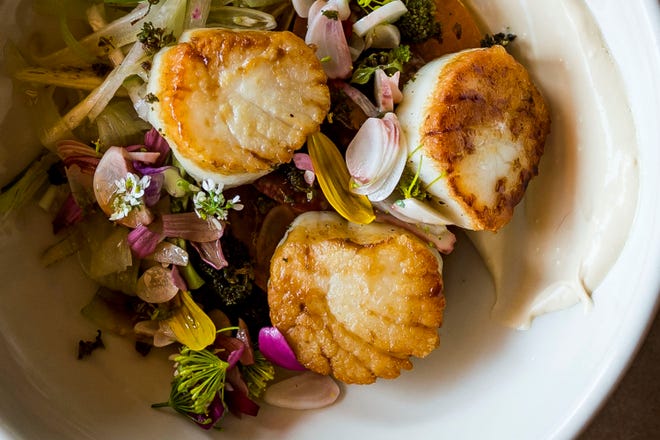 Seared Maine scallops on a bed of heirloom tomatoes, an herb flower medley, and blue pickled garlic with a black vinegar creama sauce is prepared by chef de cuisine Ryan Damasky on Wednesday, Aug. 15, 2018, at Fish Restaurant in Old Town Fort Collins, Colo.