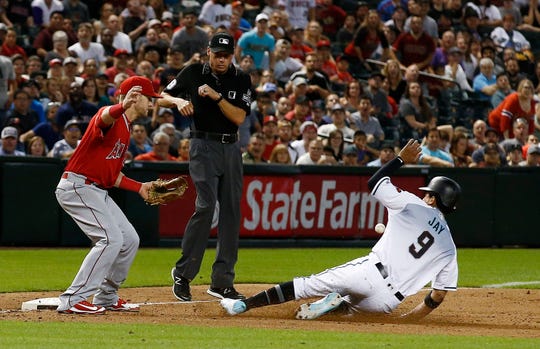 A wild throw by Angels reliever Cam Bedrosian gets past third baseman Taylor Ward (left) as Diamondbacks baserunner Joy Jay slides safely into third base in the ninth inning on Tuesday.