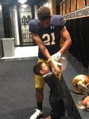 Four-star RB Gavin Williams lets his little brother, Brayden, help him put on gloves during a late-June unofficial visit to Notre Dame.