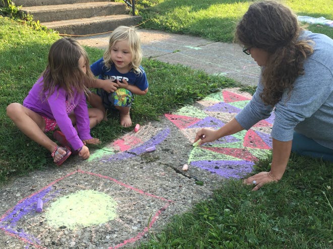 Piper Stentz, 5, left, and Kade Stentz create chalk art with Holly DeBolt outside the Woodland Club.